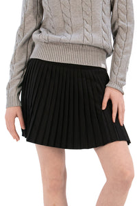Woman wearing a gray cable knit sweater and Black pleated skirt