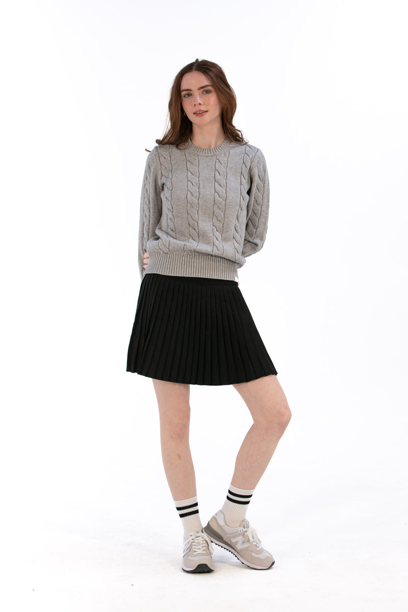 Woman wearing a gray cable knit sweater and Black pleated skirt