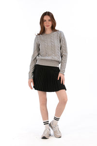 Woman wearing a gray cable knit sweater and Black pleated skirt