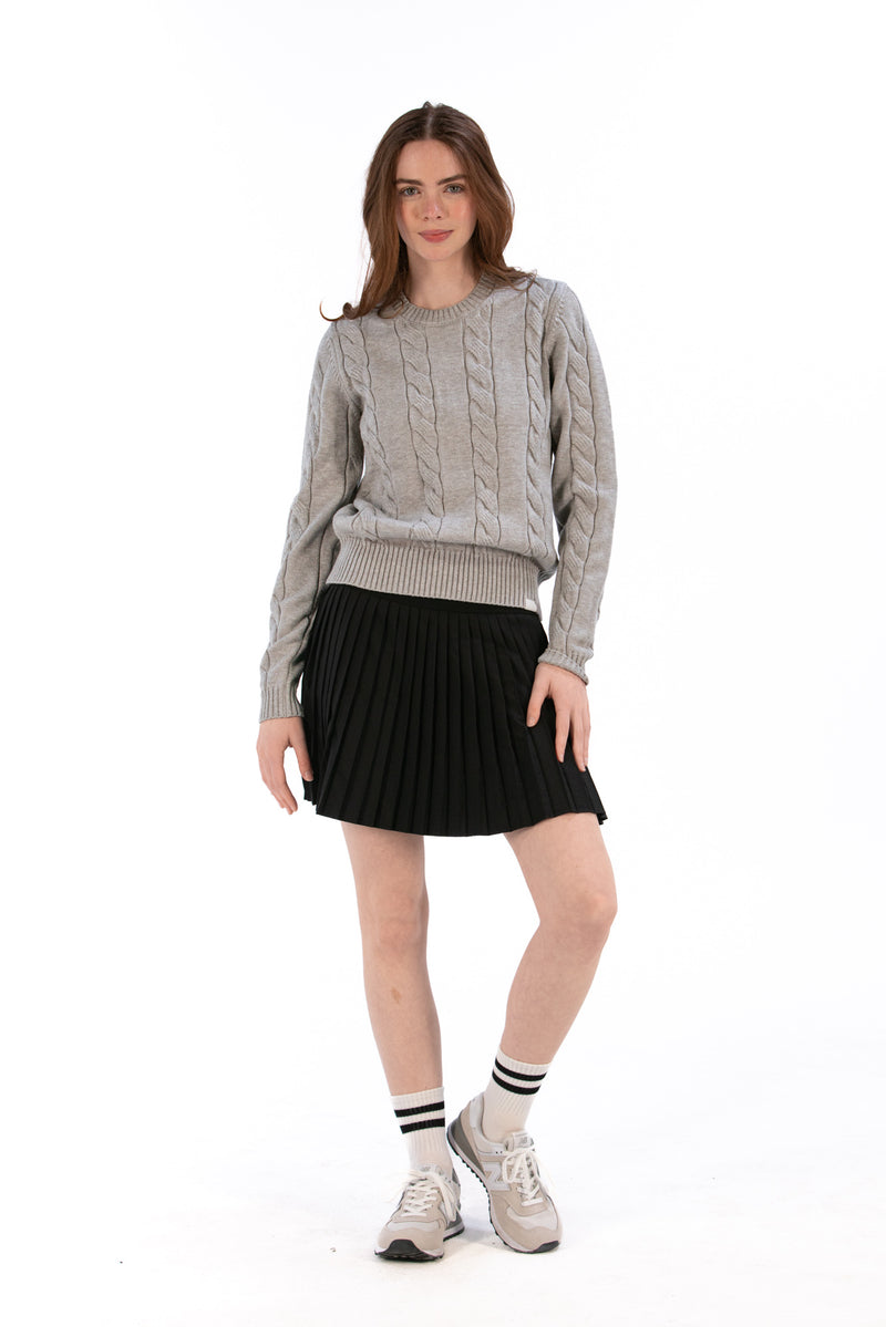 Woman wearing a gray cable knit sweater and Black pleated skirt