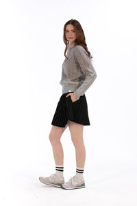 Woman wearing a gray cable knit sweater and Black pleated skirt