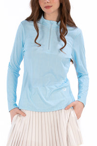 Woman wearing a Light Blue Geo long-sleeve sun blocking top with a zipper, standing against a white background.