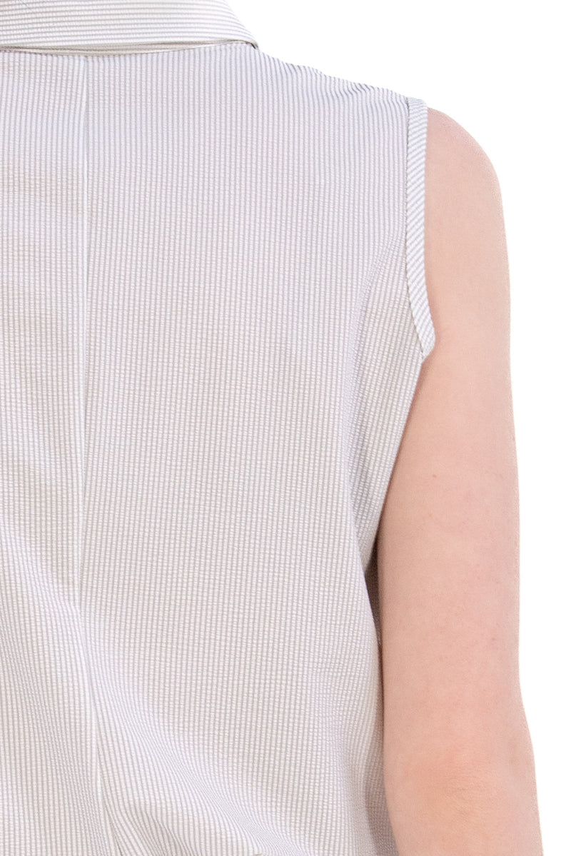 Woman wearing a sleeveless seersucker grey polo 