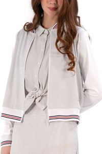 Woman wearing a Grey seersucker jacket with red accents on a white background