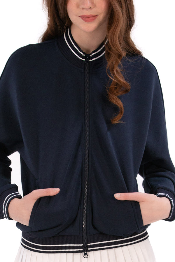 Person wearing a Navy/White bomber jacket, white shirt, pleated skirt, and white sneakers on a white background