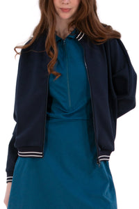 Person wearing a Navy/White bomber jacket, white shirt, pleated skirt, and white sneakers on a white background