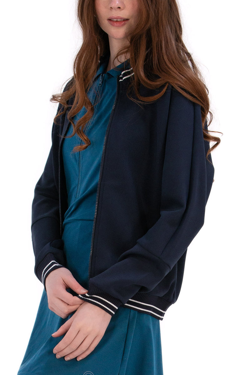 Person wearing a Navy/White bomber jacket, white shirt, pleated skirt, and white sneakers on a white background