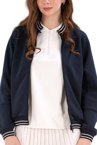 Person wearing a Navy/White bomber jacket, white shirt, pleated skirt, and white sneakers on a white background