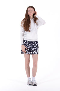 Woman wearing a White/Navy sweater and black pleated skirt on a white background