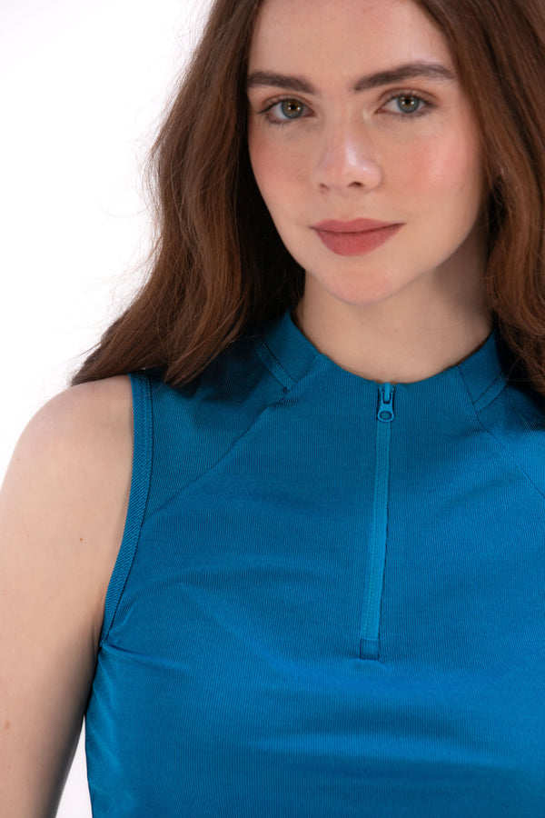Woman wearing a Blue Opal sleeveless top and navy pleated skirt on a white background