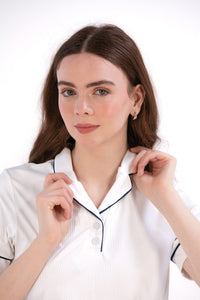 Woman wearing a white/navy top and navy skirt on a white background