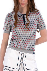 Woman wearing a Grey/Navy/Red patterned shirt, white shorts, and black socks on a white background