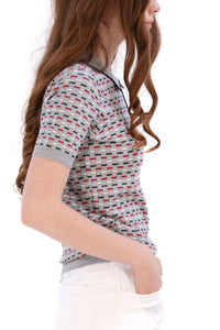 Woman wearing a Grey/Navy/Red patterned shirt, white shorts, and black socks on a white background
