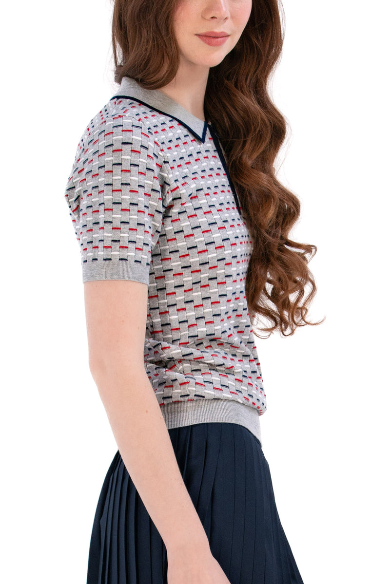 Woman wearing a Grey/Navy/Red patterned shirt, white shorts, and black socks on a white background