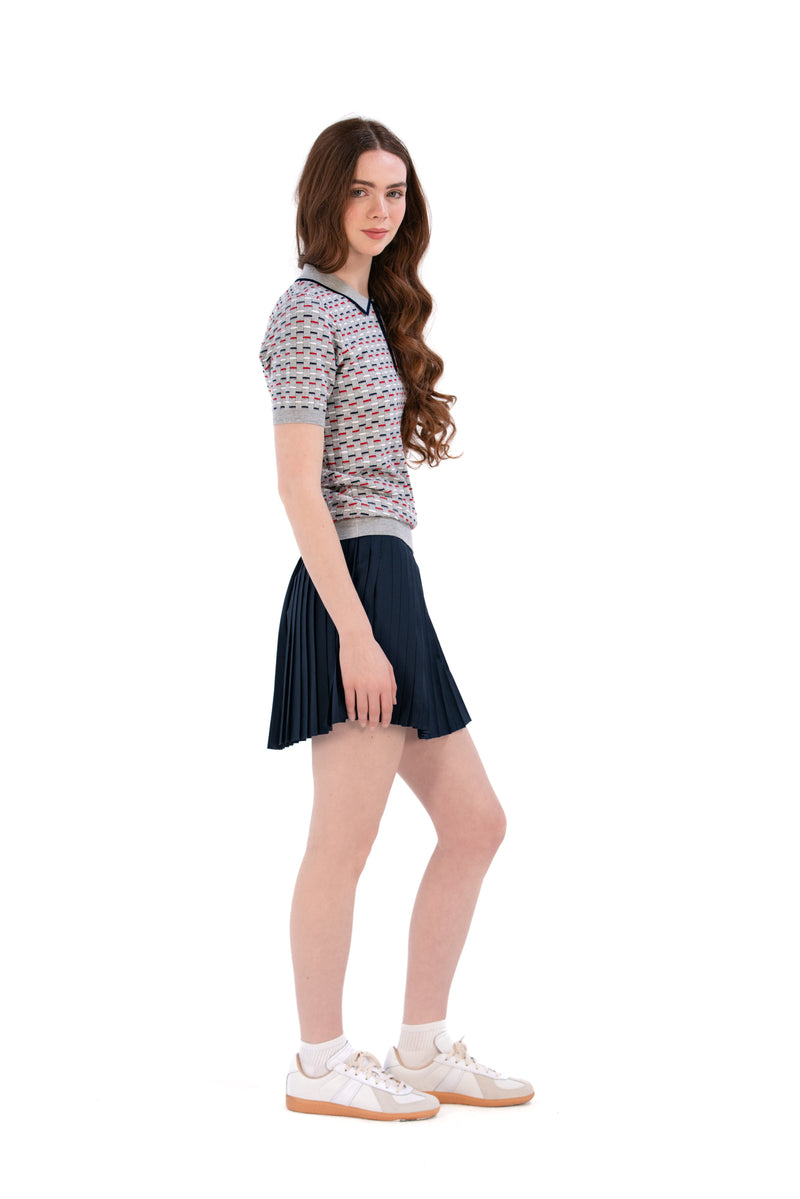 Woman wearing a Grey/Navy/Red patterned shirt, white shorts, and black socks on a white background