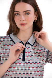 Woman wearing a Grey/Navy/Red patterned shirt, white shorts, and black socks on a white background