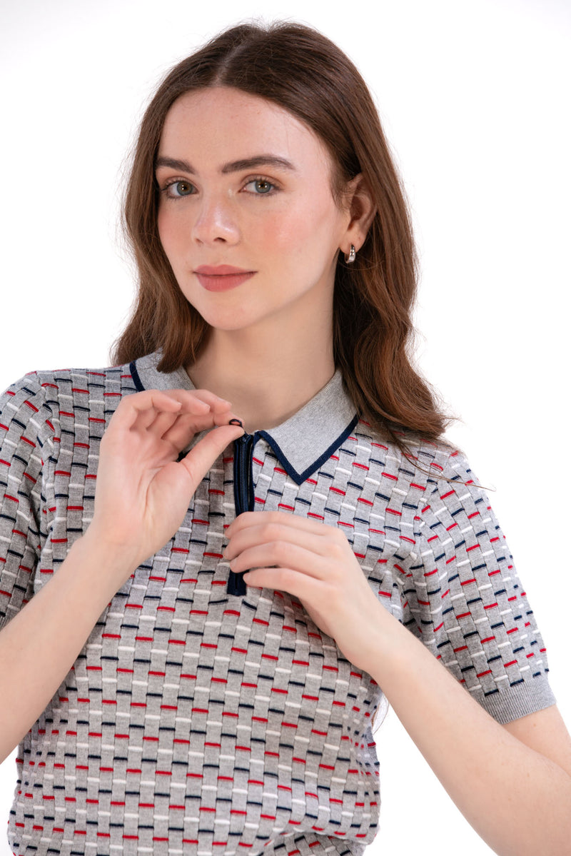 Woman wearing a Grey/Navy/Red patterned shirt, white shorts, and black socks on a white background