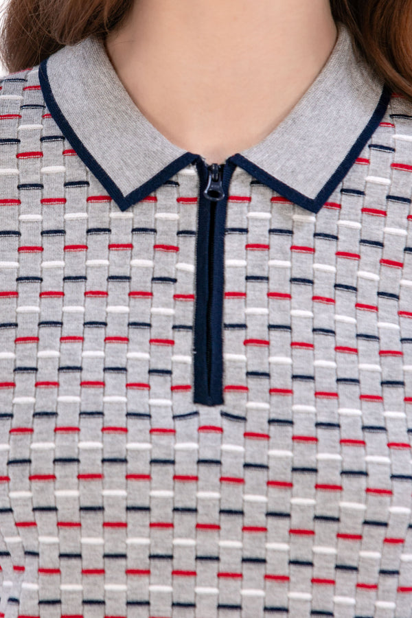 Woman wearing a Grey/Navy/Red patterned shirt, white shorts, and black socks on a white background