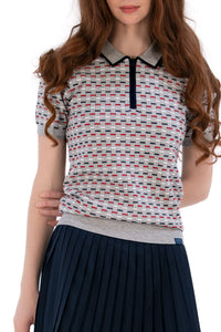 Woman wearing a Grey/Navy/Red patterned shirt, white shorts, and black socks on a white background