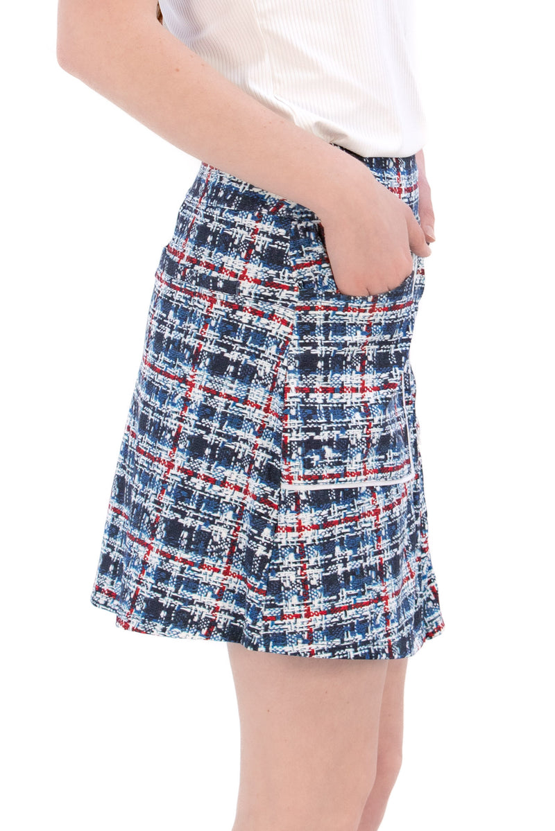 Woman wearing a navy polo shirt and plaid skirt on a white background Tall 17"