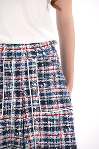 Woman wearing a navy polo shirt and plaid skirt on a white background Tall 17"