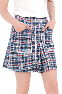 Woman wearing a navy polo shirt and plaid skirt on a white background Tall 17"