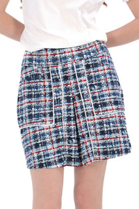 Woman wearing a navy polo shirt and plaid skirt on a white background Tall 17"