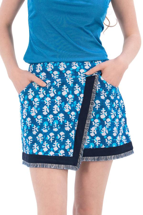 Woman wearing a blue sleeveless top and Indigo Floral patterned skirt on a white background