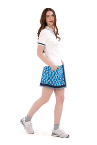 Woman wearing a white polo top and Indigo Floral patterned skirt on a white background