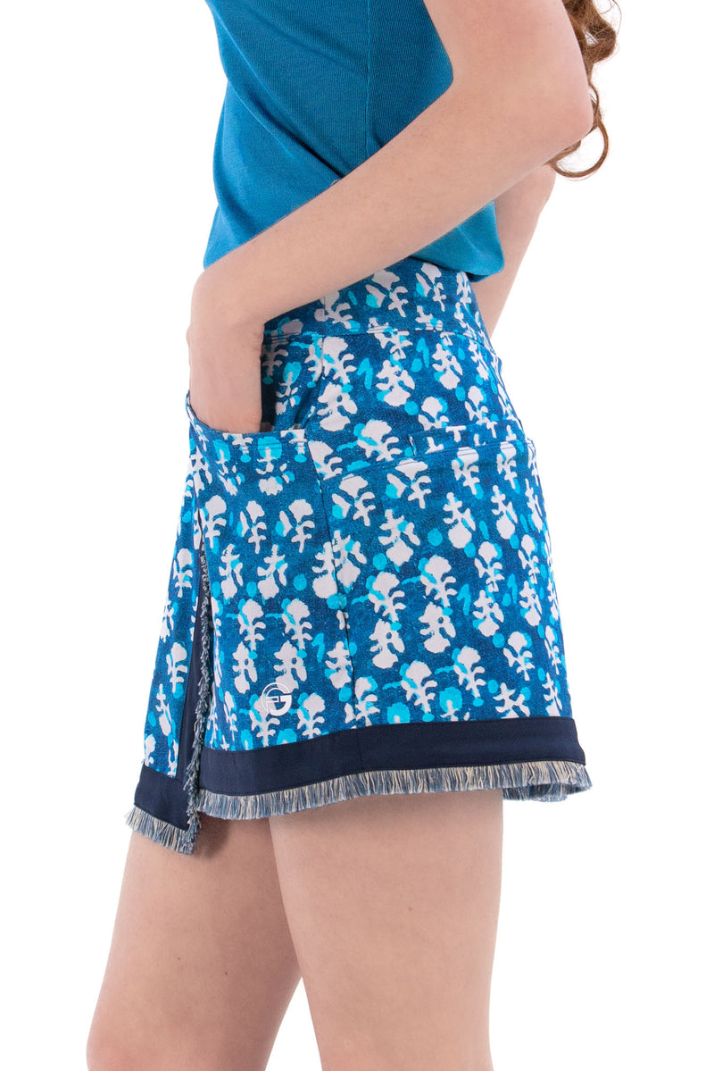 Woman wearing a blue sleeveless top and Indigo Floral patterned skirt on a white background