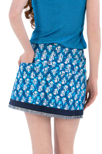 Woman wearing a blue sleeveless top and Indigo Floral patterned skirt on a white background