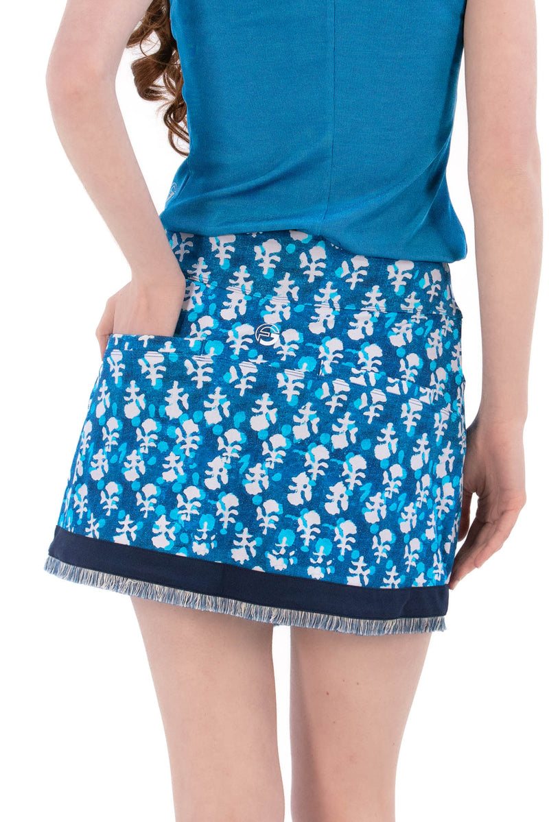Woman wearing a blue sleeveless top and Indigo Floral patterned skirt on a white background