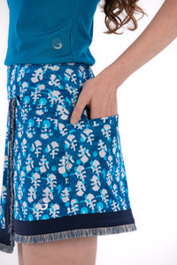 Woman wearing a blue sleeveless top and Indigo Floral patterned skirt on a white background