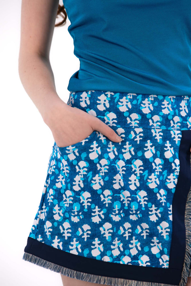 Woman wearing a blue sleeveless top and Indigo Floral patterned skirt on a white background