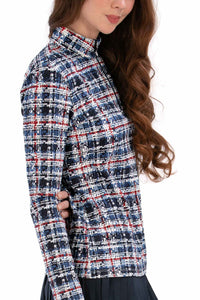 Woman wearing a Red White Blue Plaid shirt and navy pleated skirt on a white background