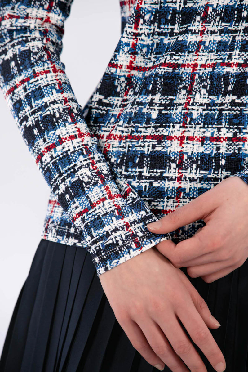 Woman wearing a Red White Blue Plaid shirt and navy pleated skirt on a white background