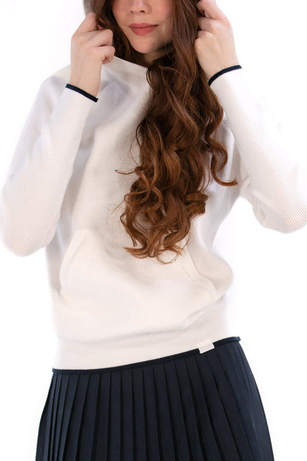 Woman wearing a White/Navy sweater and black pleated skirt on a white background