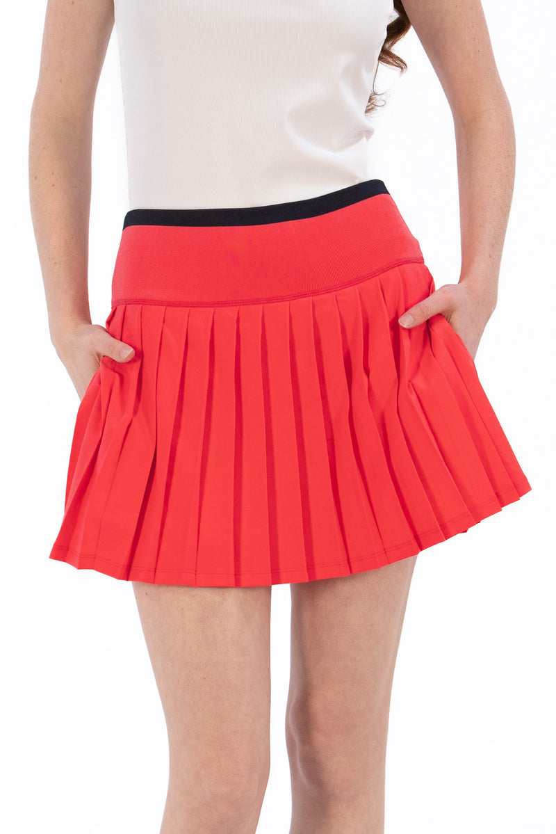 Coral pleated skirt worn by a person on a white background