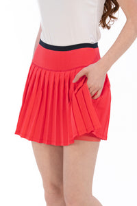 Coral pleated skirt worn by a person on a white background