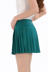 Woman wearing a white sleeveless top and Deep Jade pleated skirt on a white background