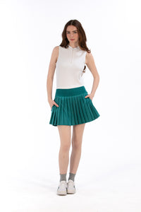 Woman wearing a white sleeveless top and Deep Jade pleated skirt on a white background
