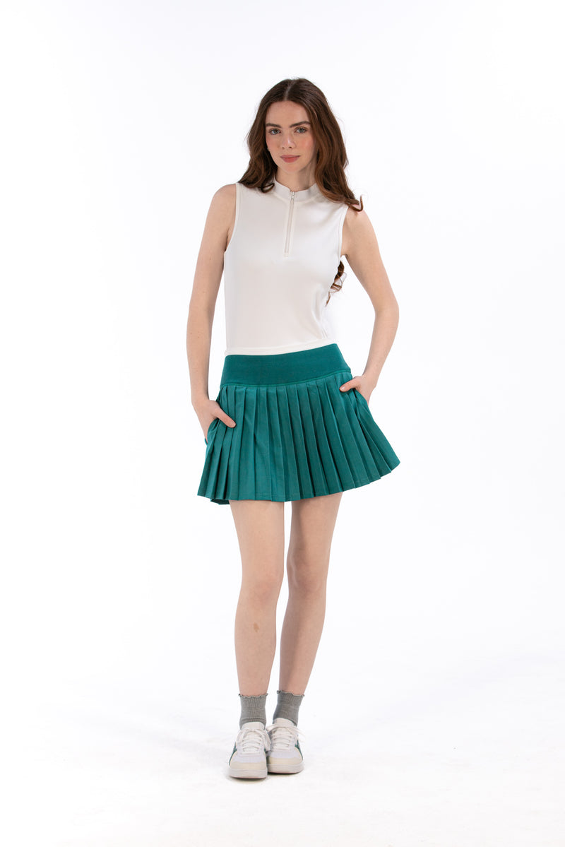 Woman wearing a white sleeveless top and Deep Jade pleated skirt on a white background