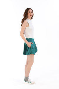 Woman wearing a white sleeveless top and Deep Jade pleated skirt on a white background