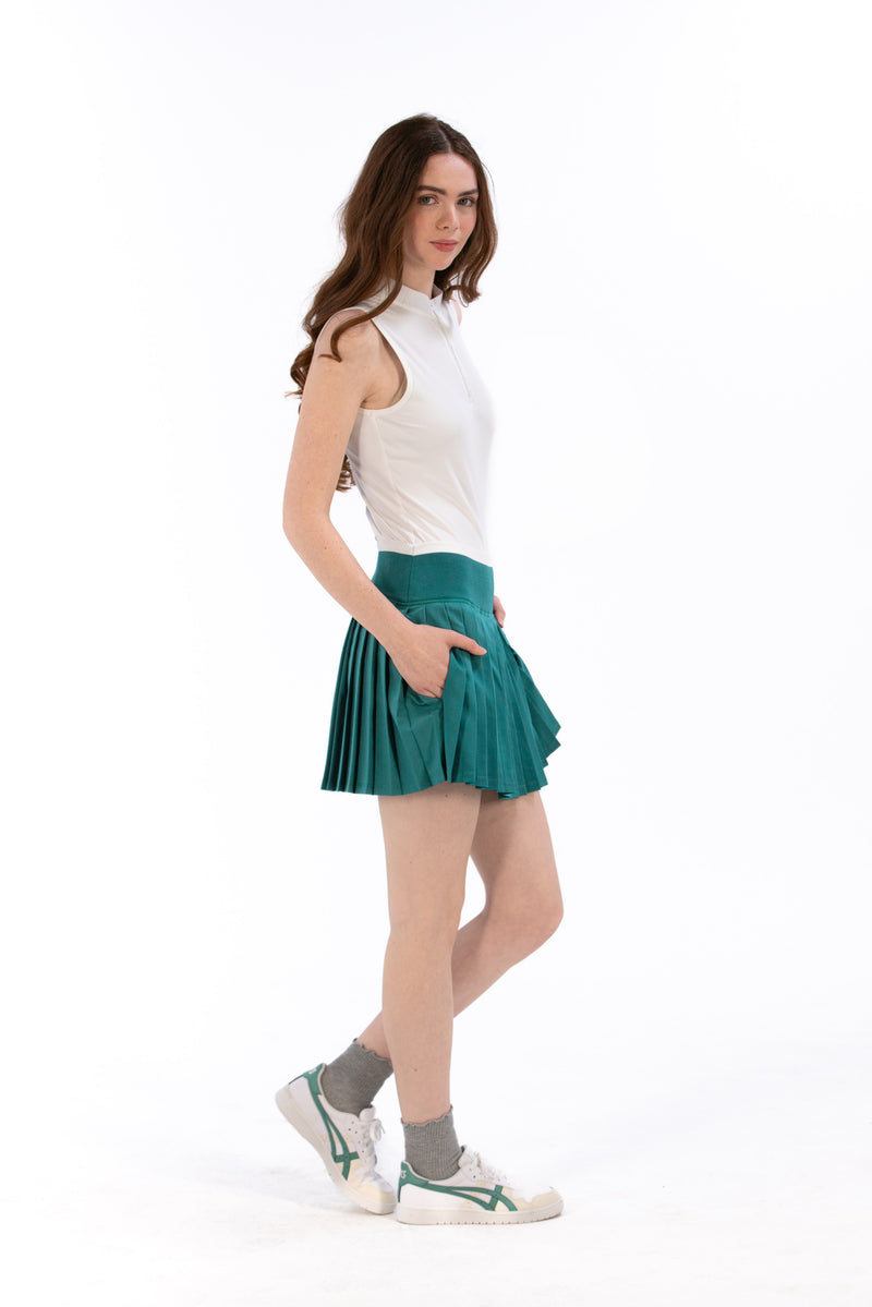 Woman wearing a white sleeveless top and Deep Jade pleated skirt on a white background