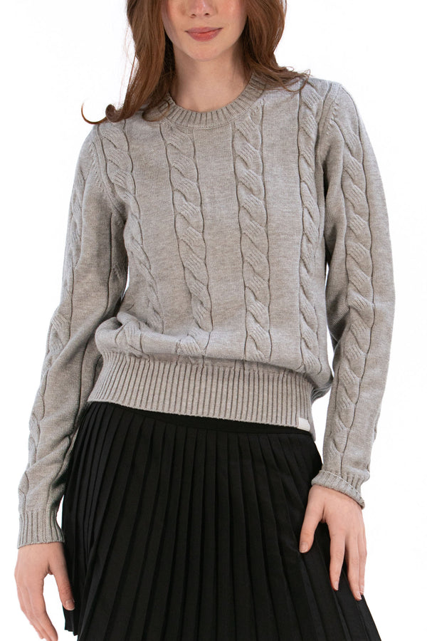 Woman wearing a marl gray cable knit sweater and black pleated skirt on a white background