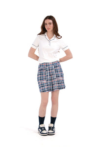 Woman wearing a white/navy top and navy printed skirt on a white background