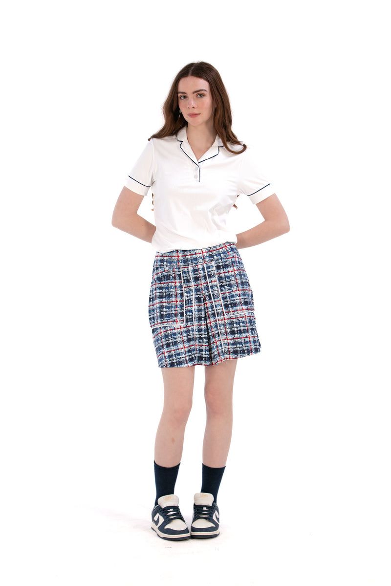 Woman wearing a white/navy top and navy printed skirt on a white background